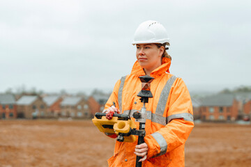 Confident woman Construction worker surveyor using surveying equipment on a cloudy day at a...