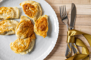 Roasted Varenyky, vareniki, pierogi, pyrohy or dumplings, filled with cheese and potatoes, on a grey gray plate