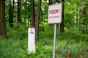 Warning sign BEWARE, NATIONAL BORDER written in Czech with border stone