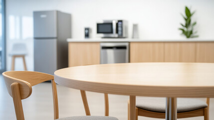 Vacant breakroom interior with round wooden table, stackable chairs, kitchen amenities, offering comfortable resting area for workplace relaxation and rejuvenation