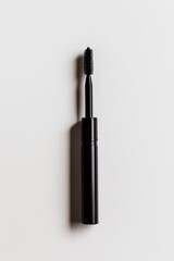 Black tube of mascara with long wavy brush on white background