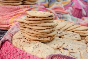 Mexican corn dough snack Sopes piled at a food market stall. 