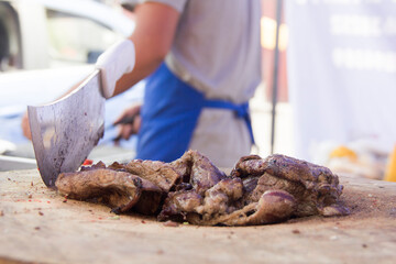 Butcher knife and grilled beef carne asada close-up at a tacos stall in rural Mexico.