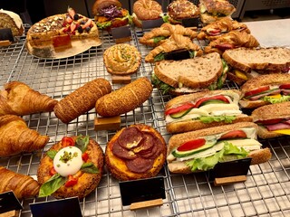 Fresh sandwiches, pies and pizza to choose from in the window of a cafe, buffet or self-service cafe. Croissant with ham and cheese. Hot pastries lie on the shelf in the cafe.