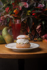 Profiterole with cream on white plate on wooden table