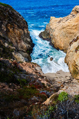 waves crashing on sandy beach with rocky cliffs