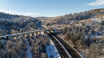 Aerial View of a Snow-Covered Highway and Bridge in a Winter Landscape