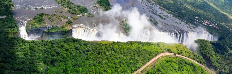 Seen from the air the mighty Zambezi River stretching wide upstream plummets into a dramatic gorge,...