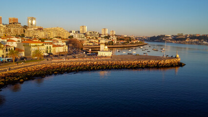 Vista capturando a deslumbrante paisagem do Porto e de Matosinhos, onde o Rio Douro encontra o Oceano Atlântico. A cena apresenta as areias douradas da praia de Matosinhos, 