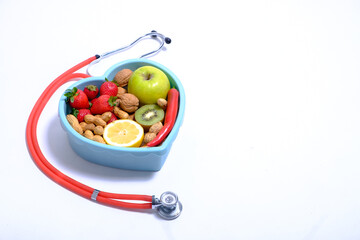 Heart shaped dish with vegetables and stethoscope isolated on white background
