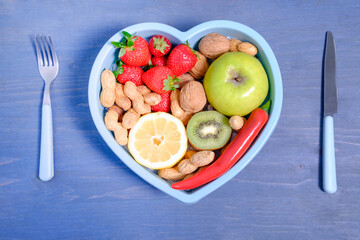 Heart shaped dish with vegetables isolated on blue wooden background