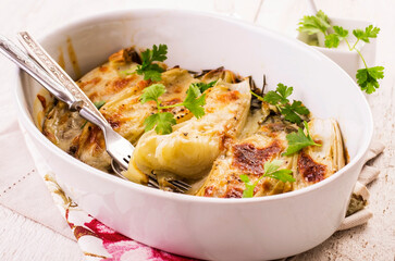 Traditional Italian chicory gratinated with buffalo mozzorella and herbs served as closeup in a classical backing form