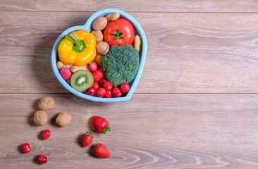 Heart shaped dish with vegetables isolated on wooden background