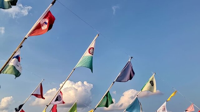 Vibrant flags from various nations flutter against a bright blue sky, celebrating diversity and global unity at a cultural event held outdoors during a sunny day.