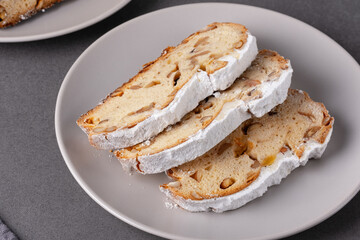 Delicious homemade stollen bread displayed on a plate with powdered sugar and chopped nuts in festive setting