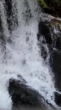 Slow motion vertical video of water cascading over rocks or waterfall. Mamquam Falls, Squamish BC