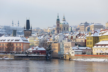 Fototapeta premium Snowy Prague Lesser Town with St. Nicholas' Cathedral in the sunny Day