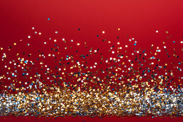 Gold and Silver Confetti scattered on a red background