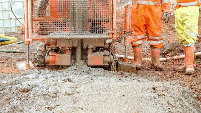 Construction crew uses small Pile rig auger drilling equipment in wet conditions at an urban site