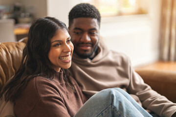 Couple shares joyful moments together on a cozy couch in a bright living room during a relaxed afternoon