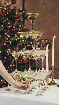 A pyramid of glasses with champagne falls. A woman's hand takes the bottom glass of sparkling wine.