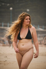 Smiling Woman in a Bikini Walking on the Beach