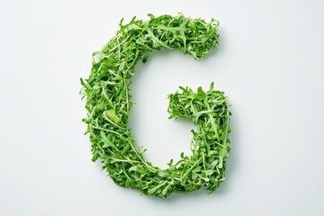 A capital G is formed with fresh green arugula sprouts against a white backdrop