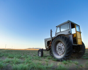 Fototapeta premium Weathered tractor and countryside scenery at twilight