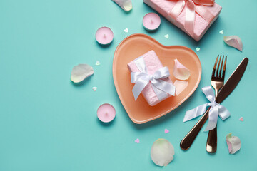 Beautiful table setting for Valentine's Day with pink rose petals, candles and gift boxes on turquoise background