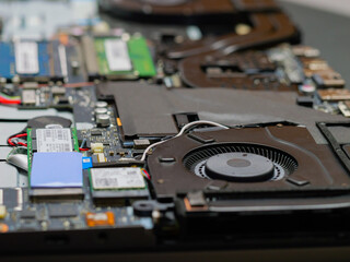 Dusty cooling fan inside laptop disassembled for cleaning closeup.