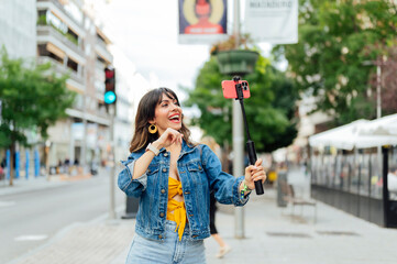 Young woman vlogging with selfie stick in the city center