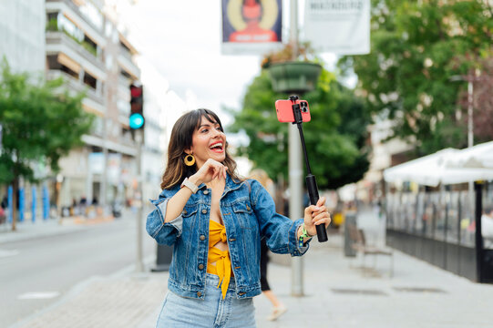 Young woman vlogging with selfie stick in the city center