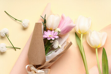 Composition with mini bouquet of beautiful spring flowers in wrapping paper on yellow background....