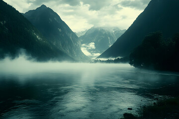 Serene misty mountain lake landscape; tranquil waters reflect dramatic peaks shrouded in fog, creating a picturesque and peaceful scene.