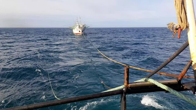 Ship refueling process in high sea. Oil chemical tanker tows fishing vessel, oceanic bunkering operation. Ecology, safety, pollution fuel transfer, shipping and environment, oil transportation.