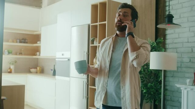 Man Taking a Phone Call in Modern Kitchen with Coffee Mug