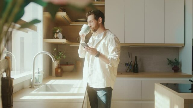 Man Using Smartphone in Stylish Kitchen with Coffee