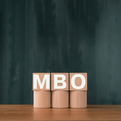 There is wood cube with the word MBO. It is an abbreviation for Management by Objectives as...