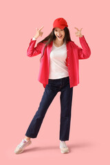 Beautiful young woman pointing at cap on pink background