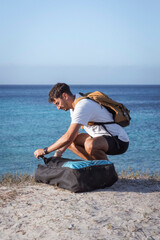 Young man unpacking paddleboard by the sea