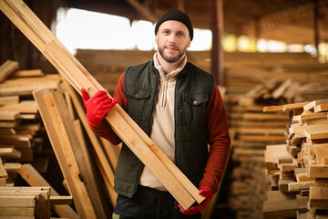 Male carpenter with wooden planks at sawmill