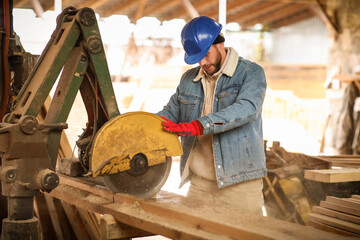 Male carpenter using sawing machine at sawmill