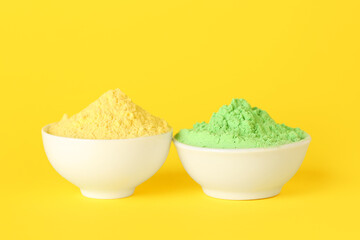 Bowls of powder pigments on yellow background