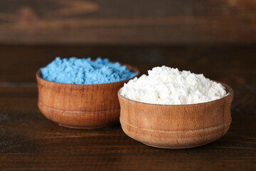 Bowls of powder pigments on wooden table, closeup