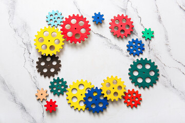 Frame made of wooden gears on light background