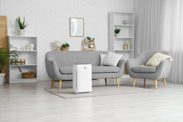 Interior of light living room with air purifier, sofa and armchair