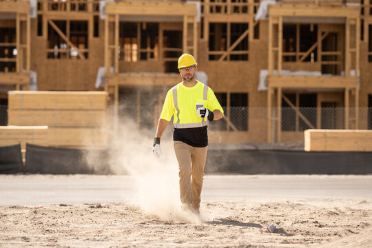 Construction worker having coffee break on construction site. A man builder in a helmet and goggles drinks a hot drink. Mature construction worker taking a break on site and drinking a coffee beverage