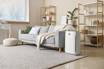 Interior of living room with air purifier, sofa and shelf units