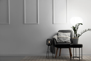 Interior of living room with armchair, table and glowing lamps in evening