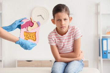 Teenage girl with appendicitis and doctor holding paper digestive system in clinic